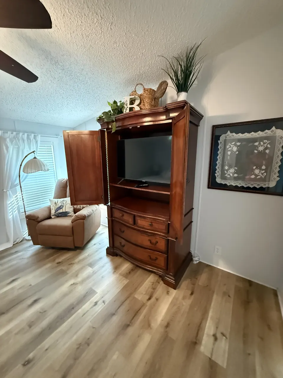 Bedroom sitting area at Sapelo House with a TV armoire, reading chair, and bright window light.