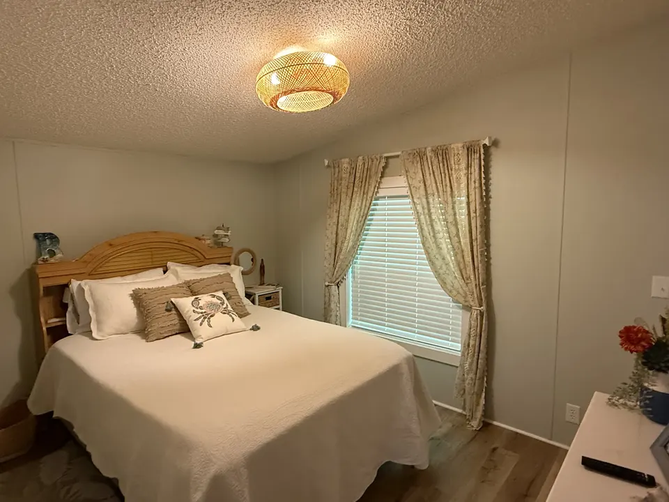 Bright coastal guest bedroom at Sapelo House with a neatly made bed, soft curtains, and natural light.