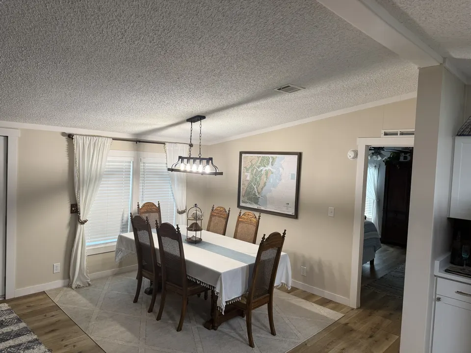 Dining room at Sapelo House with a wood table, upholstered chairs, and natural light beside the kitchen.
