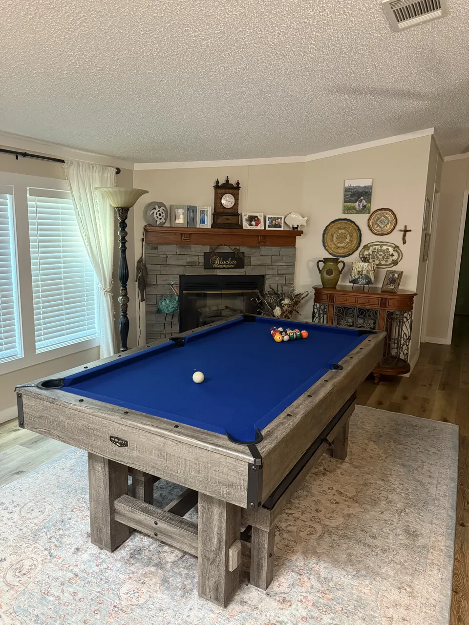 Game room at Sapelo House with a blue pool table, stone fireplace, and comfortable coastal decor.