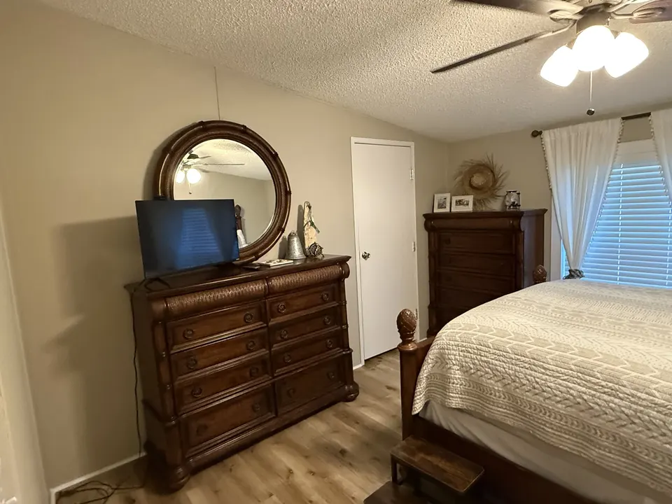 Guest bedroom at Sapelo House with a TV, wood dresser, bed, and window curtains.