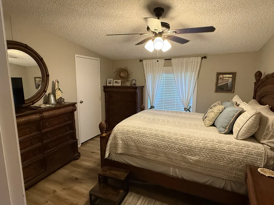 Guest bedroom at Sapelo House with a bed, wood dresser, mirror, and warm flooring.