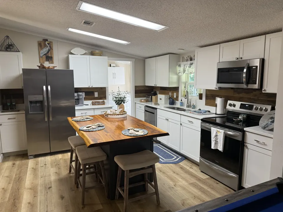 Sapelo House kitchen with white cabinets, stainless steel appliances, and a wood island with seating.