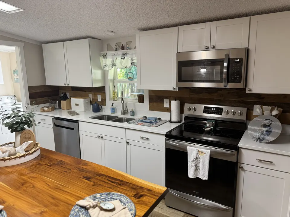 Sapelo House kitchen with white cabinets, stainless appliances, wood island, and coastal serving details.