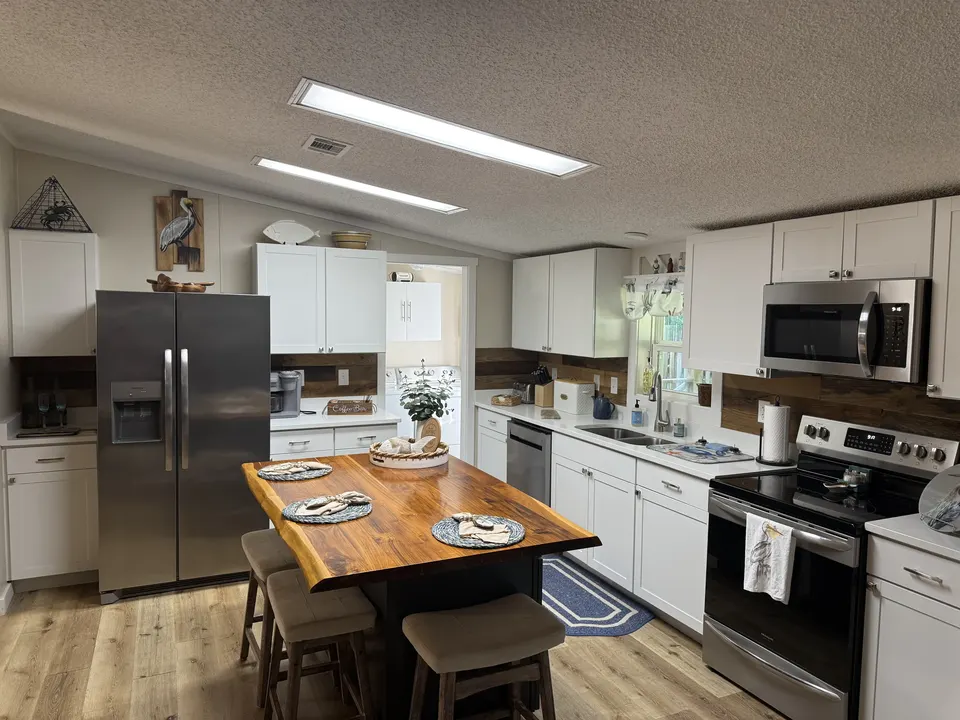 Open kitchen at Sapelo House with a central island, white cabinetry, and stainless steel appliances.