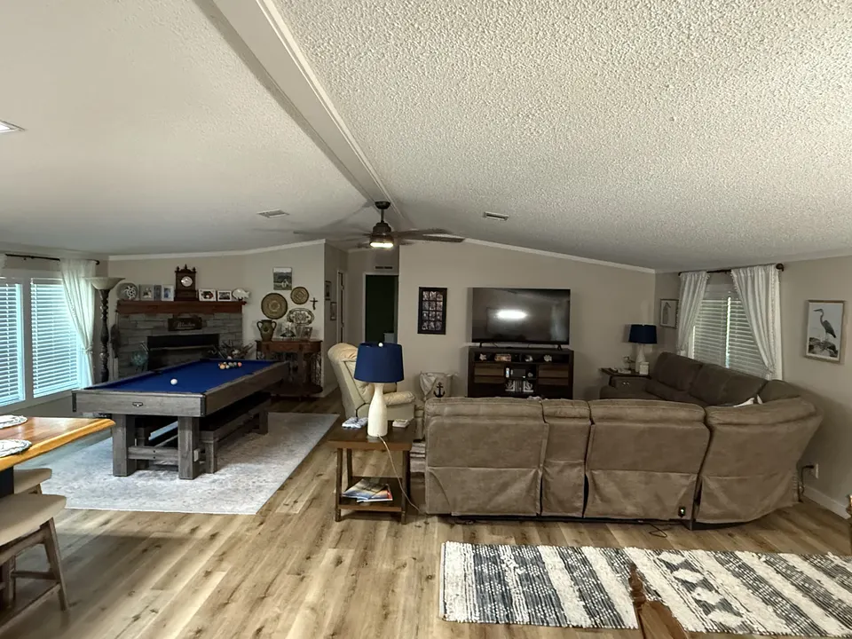 Open living room at Sapelo House with sectional seating, a pool table, and bright windows.