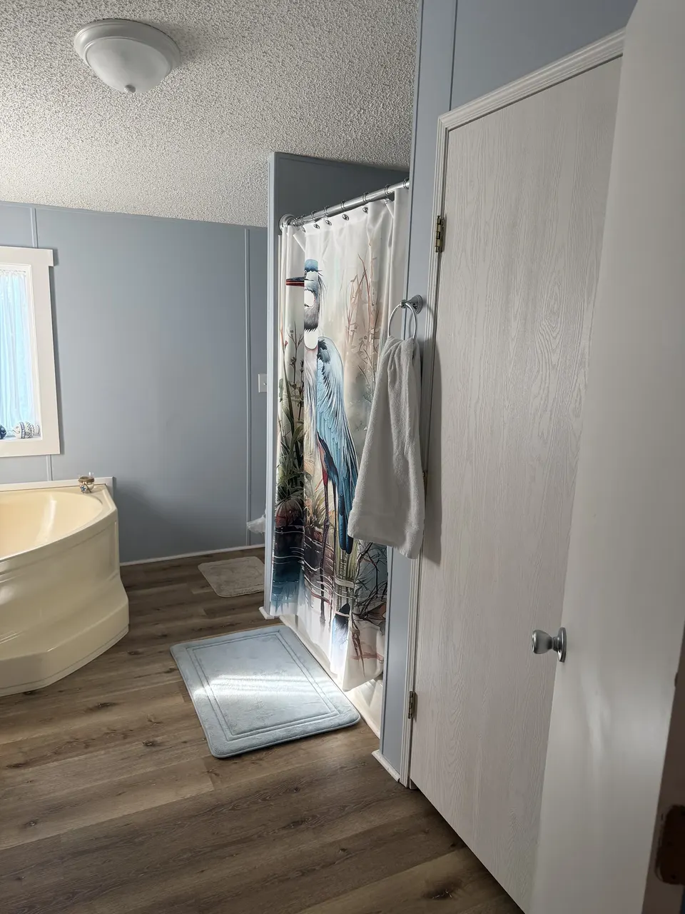 Primary bath at Sapelo House featuring a soaking tub, walk-in shower, towels, and closet storage.
