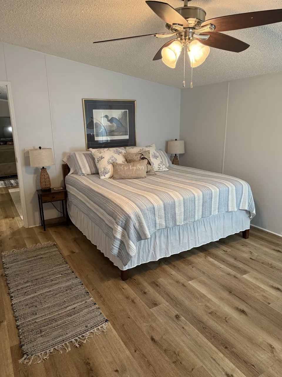 Primary bedroom at Sapelo House with a large bed, coastal bedding, nightstands, and warm wood floors.